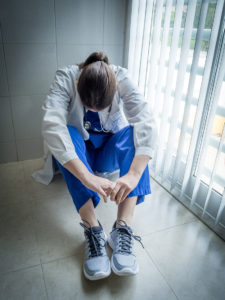 Tired doctor sitting alone in hospital floor near window